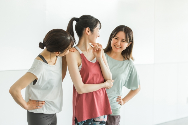ヨガウェア姿でレッスン前後に会話する女性3人のイメージ写真（店舗の実景ではありません）