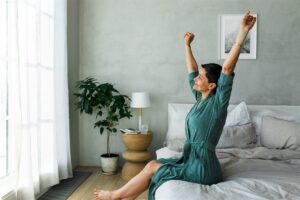 ベッドの上で朝に腕と背中を伸ばす女性のイメージ写真