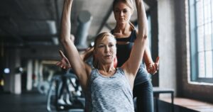 パーソナルトレーナーのサポートを受けて運動する女性のイメージ